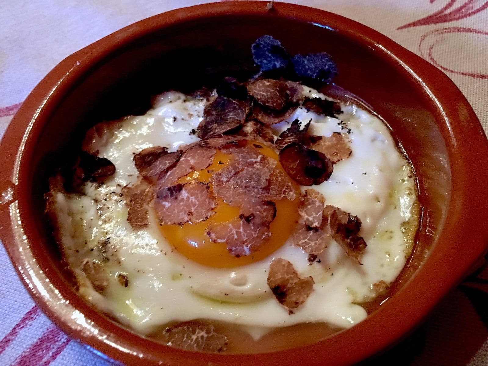 Fried egg with a soft yolk and shavings of fresh truffle in a terracotta dish