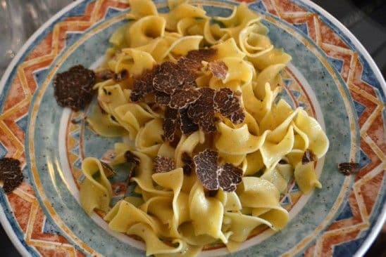 Plate of homemade tagliolini pasta coated with butter and fresh truffle shavings