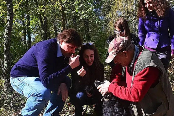 Group of people smelling the just found truffle during a truffle hunt with expert hunter and trained dog