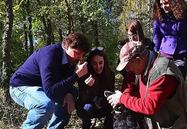 Group of people smelling the just found truffle during a truffle hunt with expert hunter and trained dog